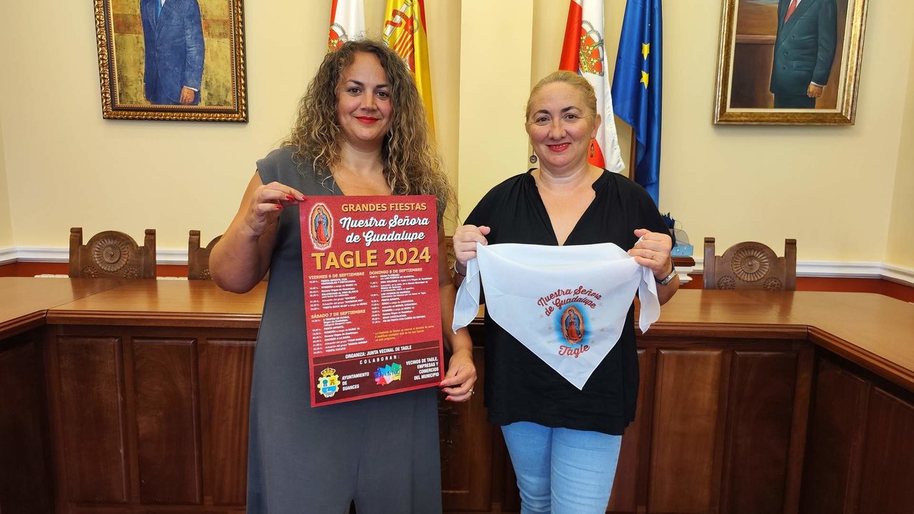 La concejala Raquel Fernández y la presidenta de la Junta Vecinal, Rebeca Pernía, con el cartel y el pañuelo de las fiestas de Guadalupe